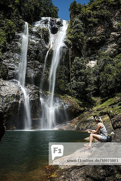 Eine junge Frau sitzt am Cunca Rami Wasserfall; Flores  Indonesien'.