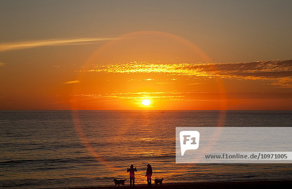 'A halo around the glowing sun as it sets over the ocean and an orange sky; Chiclana de la Frontera  Andalusia  Spain'