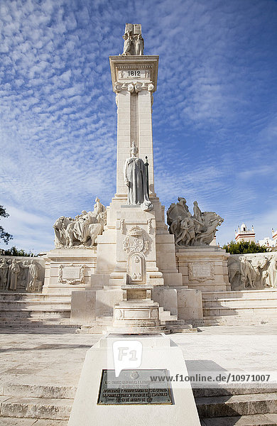 In eine Mauer eingemeißelte menschliche Figuren und ein Turm mit einer Statue vor einem blauen Himmel mit Zirruswolken; Andalusien  Spanien'.