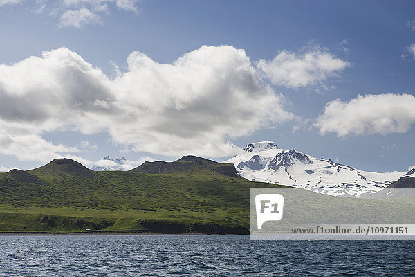 'Green Shores And Snow Covered Roundtop Mountain On Unimak Island  The Easternmost Island Of The Aleutian Chain  From Ikatan Bay; Southwest Alaska  United States Of America'