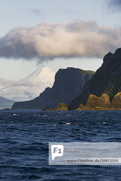 Shishaldin-Vulkan und Isanotski-Gipfel im Hintergrund der zerklüfteten Felsküste von Cape Pankof auf der Insel Unimak  östliche Aleuten; Südwest-Alaska  Vereinigte Staaten von Amerika'.