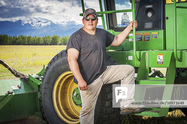 Landwirt steht vor seinem selbstfahrenden Scheibenmäher; Delta Junction  Alaska  Vereinigte Staaten von Amerika