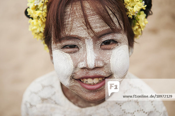 'Young girl with white face paint and flowers in her hair; Bagan  Myanmar'