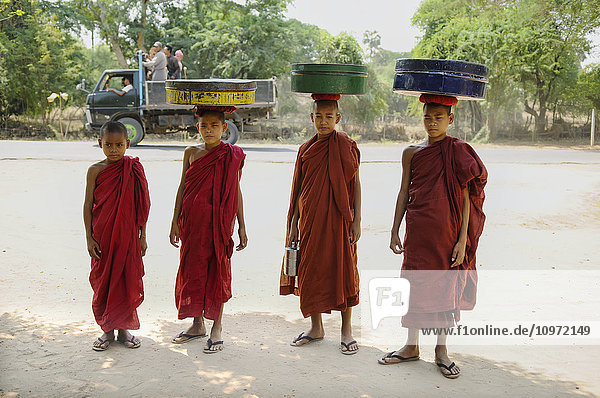 'Novice buddhist monks carrying food on their heads; Bagan  Myanmar'
