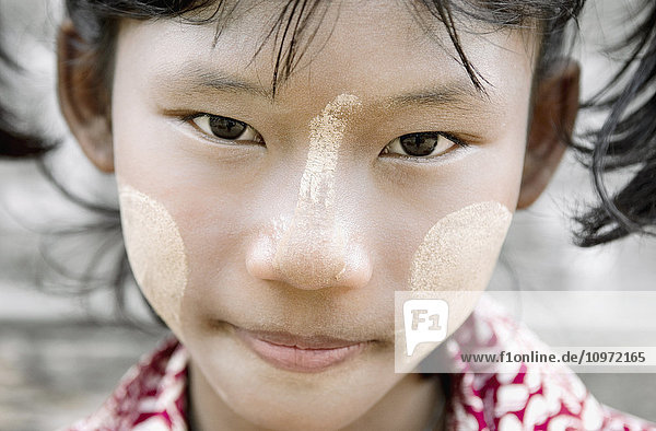 'Close up portrait of a young girl with white face paint; Bagan  Myanmar'