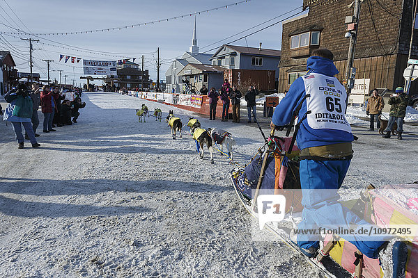 Wade Marrs runs into the finish chute on the way to the Nome burl arch finish line during Iditarod 2015