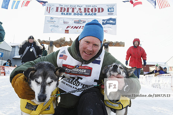 Mats Pettersson umarmt seine Leithunde an der Ziellinie in Nome während des Iditarod 2015