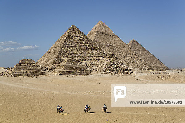 'Local men on horses the Giza Pyramids; Giza Egypt'