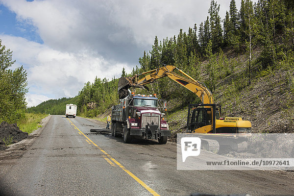 Ein Wohnmobil fährt an einem Straßenbautrupp vorbei  der auf dem Alaska Highway westlich von Fort Nelson  British Columbia  Kanada  im Sommer unterwegs ist.