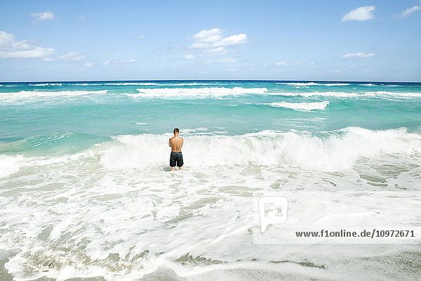 Mann  der im Meer steht  während sich die Wellen am Ufer brechen; Varadero  Kuba