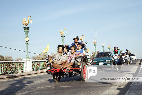 Mehrere Personen auf einem Motorroller beim Überqueren einer Brücke; Chiang Mai  Thailand'.