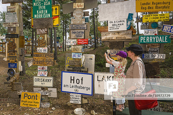 Mother and daughter explore the Signpost Forest  Watson Lake  Yukon Territory  Canada  summer