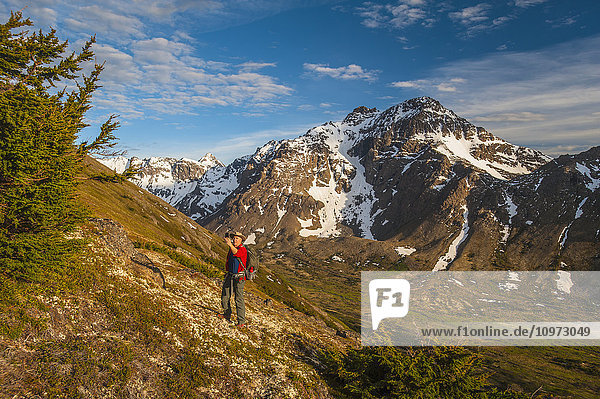 Wanderer auf einem Hügel mit Blick auf das Powerline Pass-Tal und den Wanderweg macht ein Selfie  Chugach State Park  Southcentral Alaska