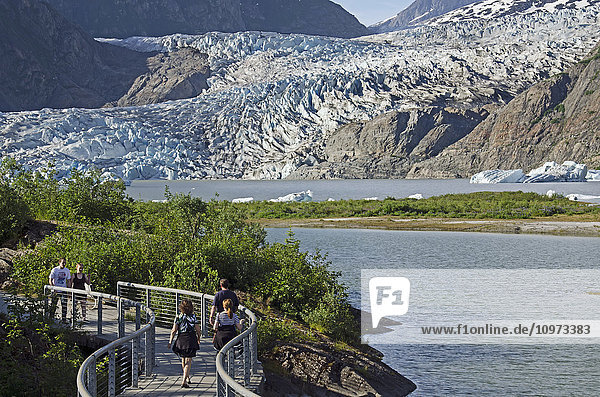 Tourists walk along paved path viewing Mendenhall Glacier in Tongass National Forest  Southeast Alaska  summer