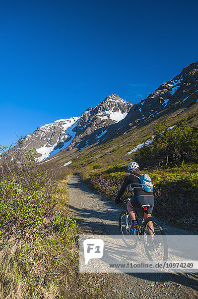 Eine Frau fährt mit ihrem Fahrrad im Powerline Pass Valley im Chugach State Park in Süd-Zentral-Alaska.