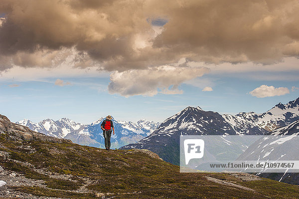 Ein Mann wandert in der Nähe des Harding Icefield Trail mit den Chugach Mountains und dem Resurrection Valley im Hintergrund  Kenai Fjords National Park  Southcentral Alaska