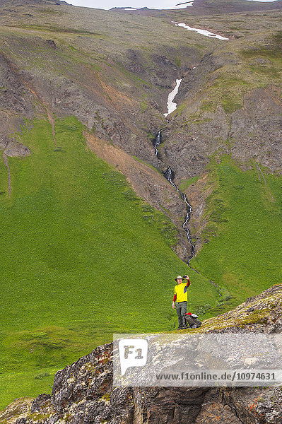 Ein Mann  der im Hanging Valley wandert  macht ein Selfie mit einem Wasserfall im Hintergrund in South Fork in der Nähe von Eagle River  Southcentral Alaska  Sommer
