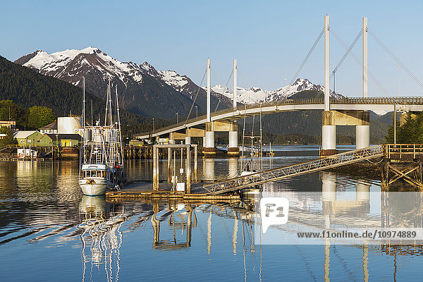 Ein Fischerboot angedockt auf dem ruhigen Wasser im Hafen von Sitka mit der O'Connell-Brücke im Hintergrund  Sitka  Südost-Alaska  USA  Sommer