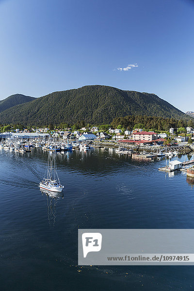 A fishing boat motors out of Sitka Harbor on a clear day  Southeast Alaska  USA  Summer