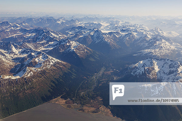 Aerial view of snow covered peaks in the Chugach Mountains with Girdwood in the foreground  Southcentral Alaska  USA  Summer