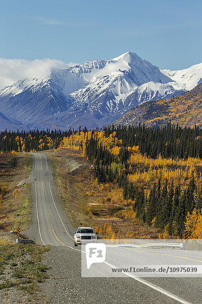 Autofahrten auf dem Alaska Highway mit schneebedeckten Gipfeln der St. Elias Mountains und bunten Bäumen im Hintergrund  Yukon Territory  Kanada  Herbst