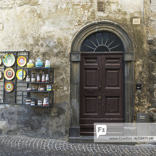 'A wooden door and a display unit with colourful ceramics on display; Orvieto  Umbria  Italy'