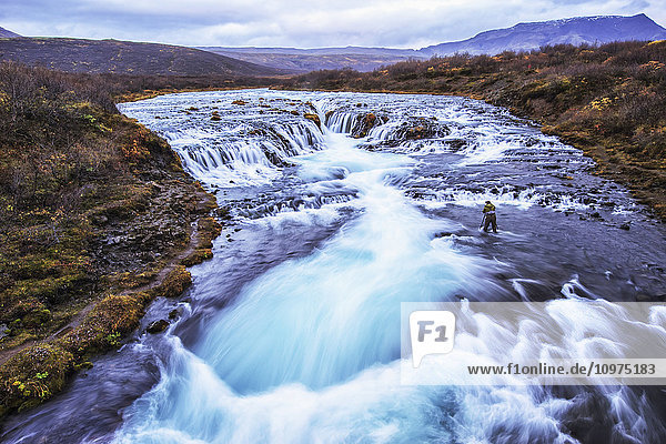 Mann beim Fotografieren des Wasserfalls Bruarfoss; Island