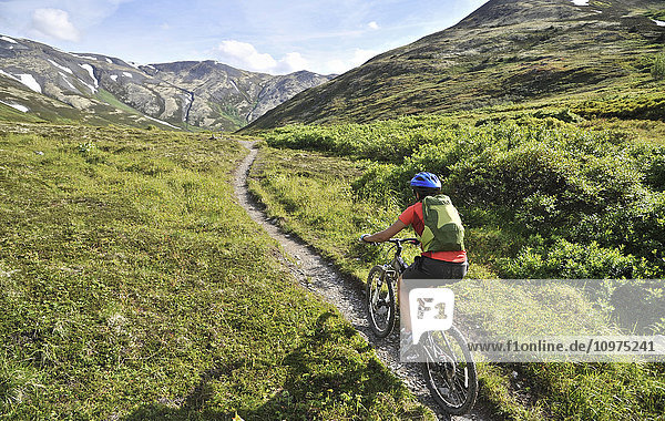 Eine Frau fährt mit einem vollgefederten Mountainbike auf dem Resurrection Pass Trail im Chugach National Forest  Kenai Peninsula  Süd-Zentral-Alaska