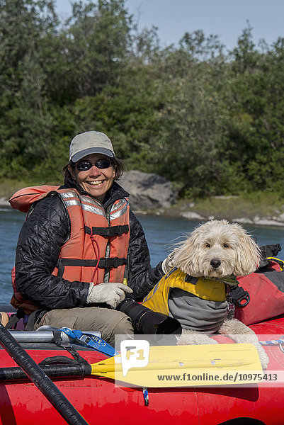 Frau und ihr Golden Doodle sitzen in einem Floß im Sonnenschein auf der Marsh Fork des Canning River im Arctic National Wildlife Refuge  Sommer  Alaska