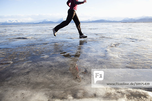 Woman running on the ice covered beach in Homer  Kenai Peninsula  Southcentral Alaska