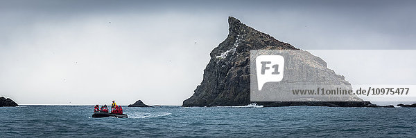 'Inflatable cruises towards jagged rock at sea; Antarctica'