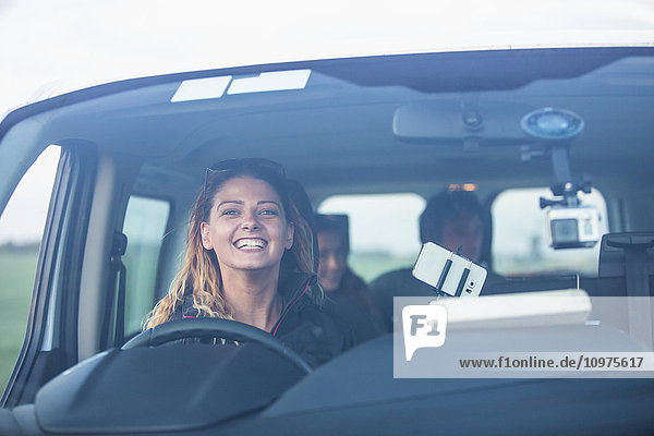 'A young woman smiles from the driver's seat of a vehicle while looking through the windshield; Egmond aan Zee  Holland'