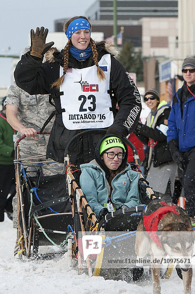 Anna Berington und ihr Team verlassen die feierliche Startlinie mit einem Iditarider während des Iditarod 2016