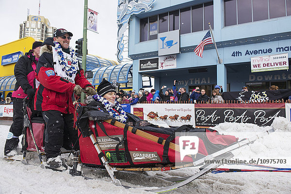 Paul Gebhardt und sein Team verlassen die feierliche Startlinie mit einem Iditarider während des Iditarod 2016