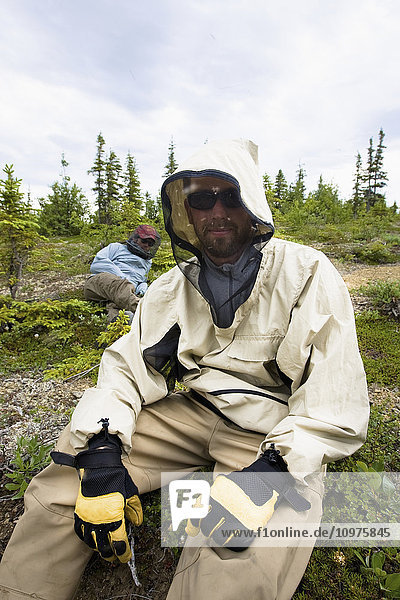 Zwei Fischer tragen Moskitonetze und Insektenschutzhemden  während sie eine Pause am Koktuli River machen  Bristol Bay Area  Südwest-Alaska  Sommer