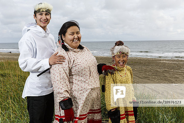 Yupik-Inupiag Eskimo young man & Yupik Eskimo girls stand in grass along Bering Sea shore  Nome  Alaska