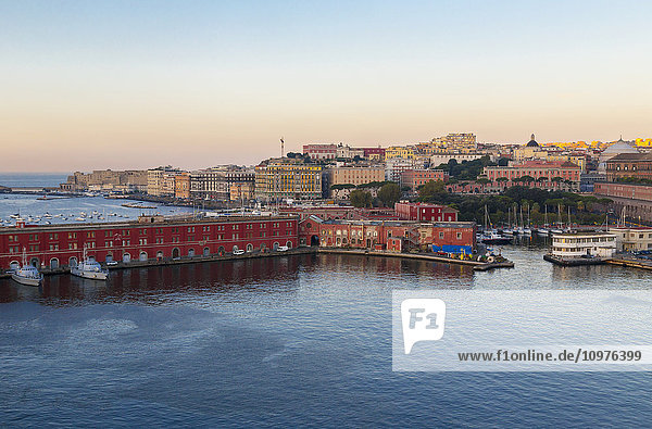 Eine weite Landschaftsansicht des Hafens von Neapel  dem Sitz der italienischen Marine  im Vordergrund mit der historischen Altstadt von Neapel im Hintergrund in der Morgendämmerung; Neapel  Kampanien  Italien