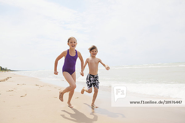'Boy and girl running on beach; Grand Bend  Ontario  Canada'