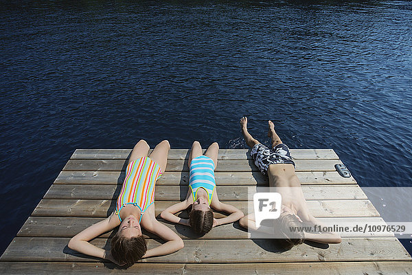 Kinder legen sich am Ende des Stegs am Crystal Lake nieder; Ontario  Kanada'.