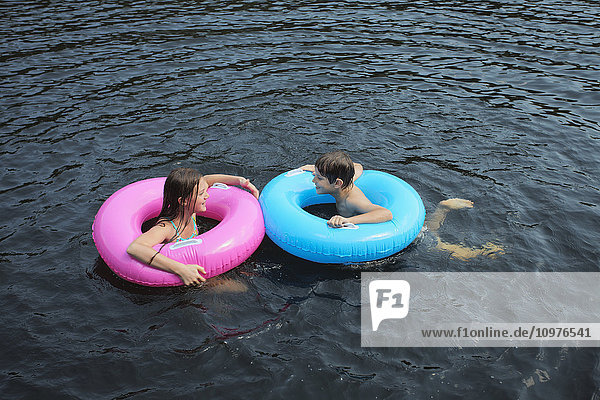 Junge und Mädchen schwimmen mit aufblasbaren Ringen im Crystal Lake; Ontario  Kanada