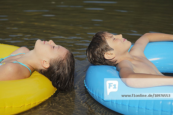 Junge und Mädchen schwimmen mit aufblasbaren Ringen auf dem Crystal Lake; Ontario  Kanada'.