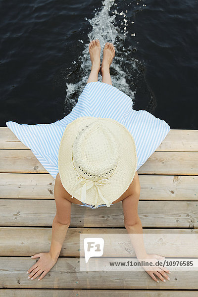 Mädchen mit Strohhut  das am Ende eines Stegs sitzt und die Füße ins Wasser hält; Ontario  Kanada'.