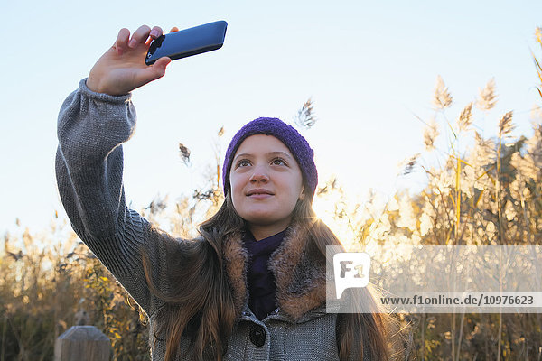 Mädchen macht ein Selfie mit Smartphone in einem Park bei Sonnenuntergang; Toronto  Ontario  Kanada'.
