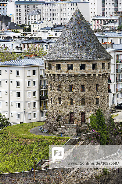Großer alter Schlossturm aus Stein auf einem Hügel mit Steinmauer und modernen Gebäuden im Hintergrund; Brest  Bretagne  Frankreich'.