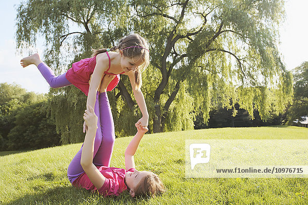 'Sisters playing balancing game in park; Toronto  Ontario  Canada'