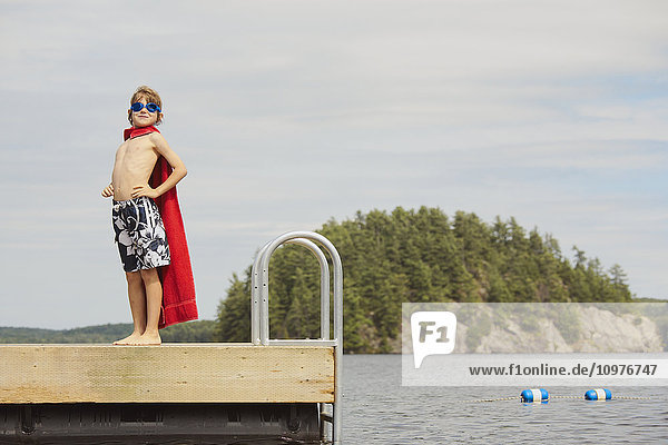 Junge steht mit Brille und Handtuch auf dem Steg und tut so  als sei er ein Superheld; Ontario  Kanada'.