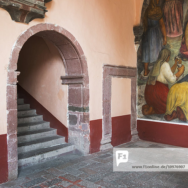 'Mural painted on a wall beside steps under an arch; San Miguel de Allende  Guanajuato  Mexico'