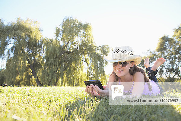 Mädchen liegt im Gras und benutzt ein Smartphone; Toronto  Ontario  Kanada'.
