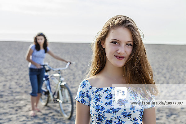'Two girls standing on a beach with bike; Toronto  Ontario  Canada'