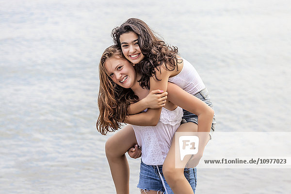 'Two girls playing piggyback at beach; Toronto  Ontario  Canada'